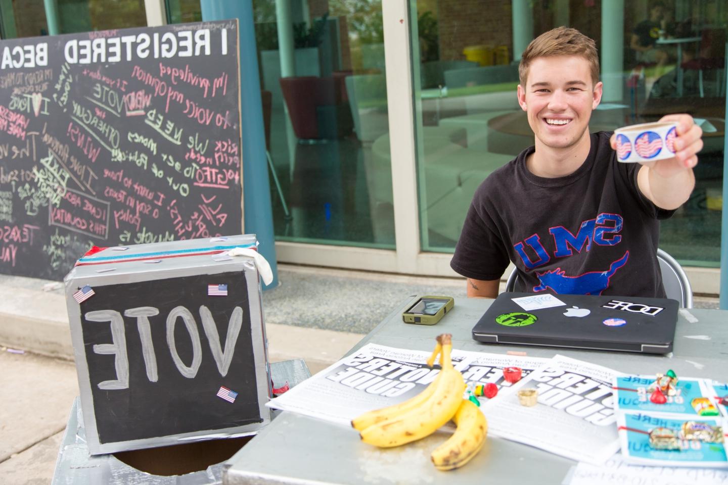 photo of a student holding a roll of stickers at an Election Vote Drive