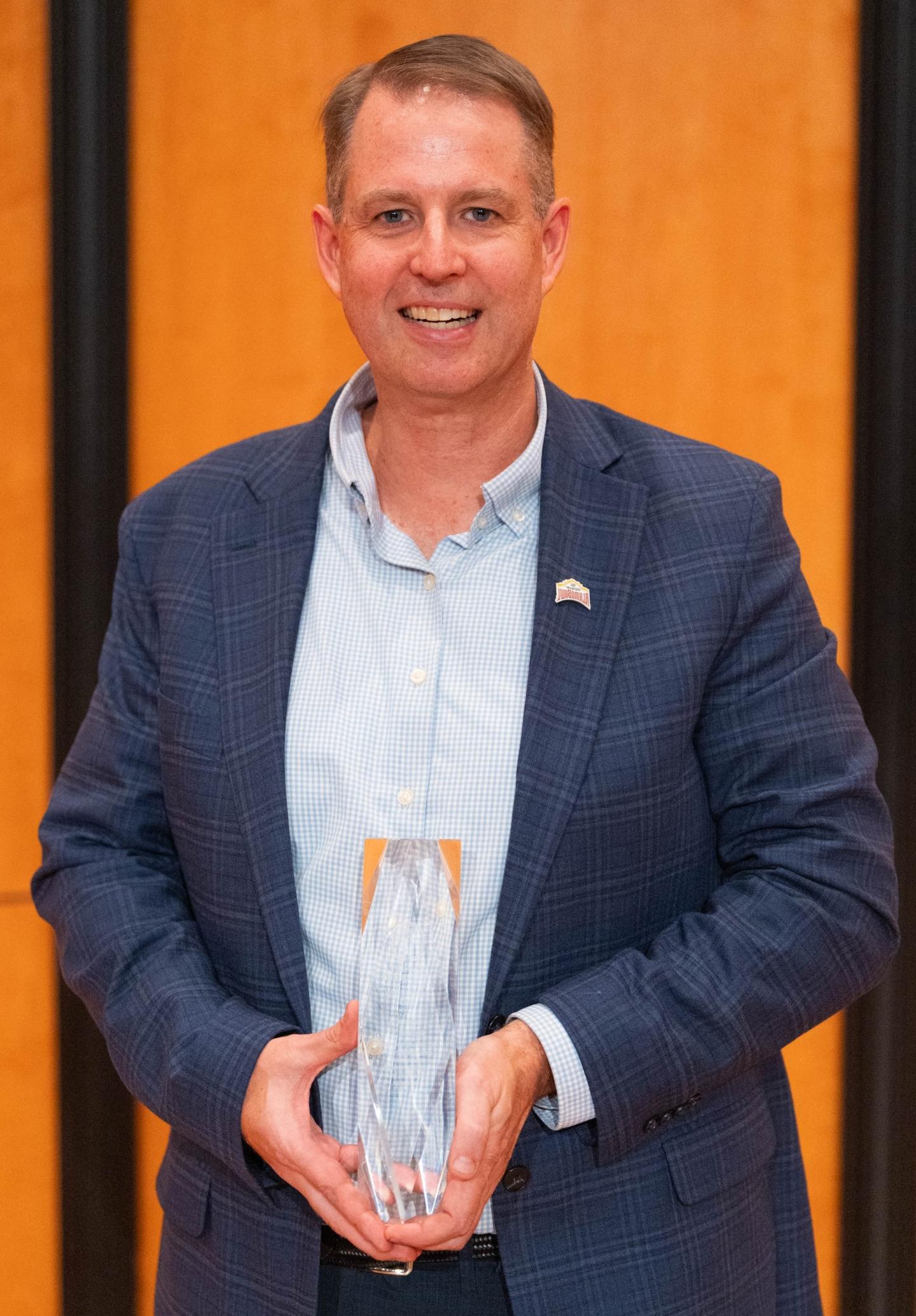 Photo of Rick Hill '91 holding an Alumni Award