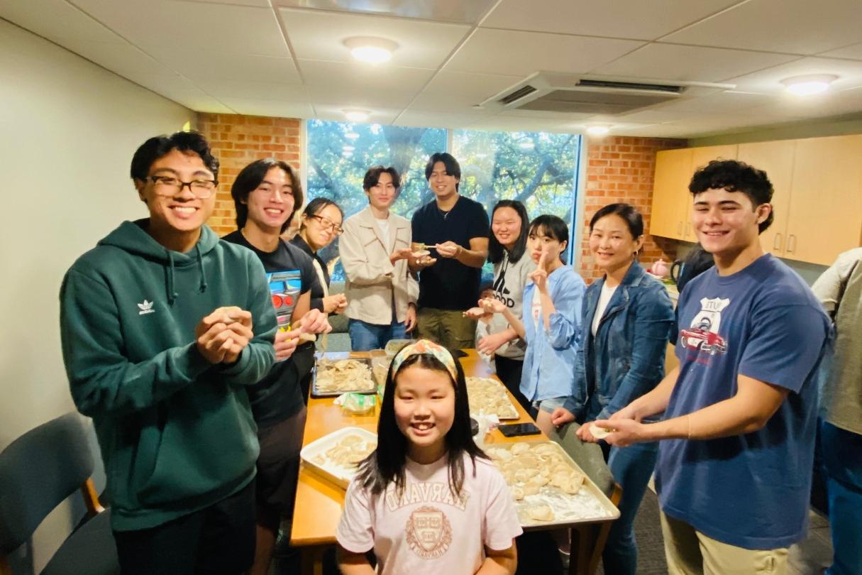 group of students standing around a table smiling and holding food