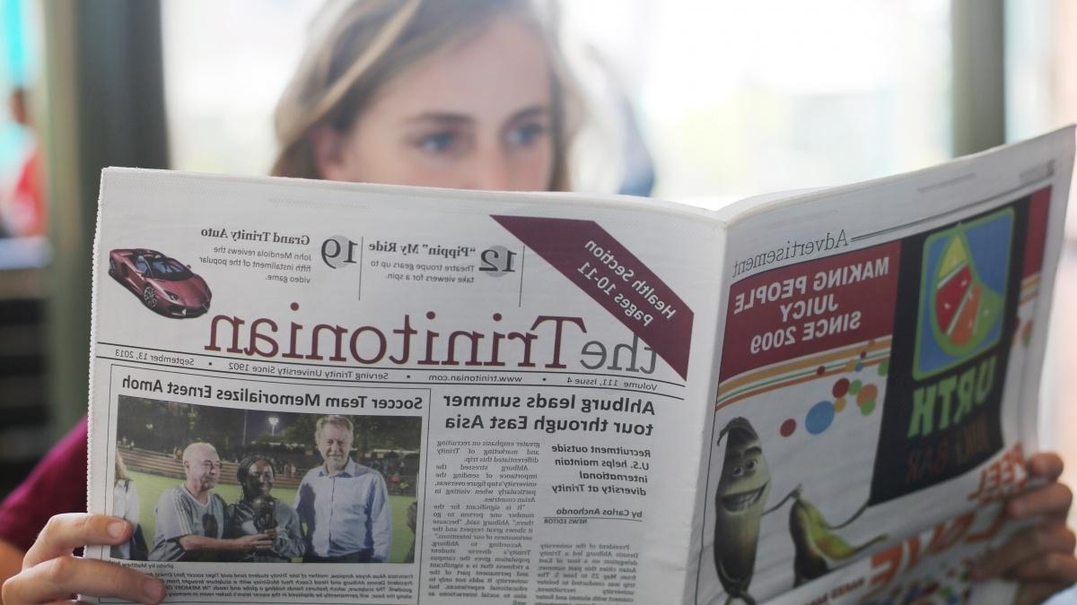  a student reads a copy of the Trinitonian