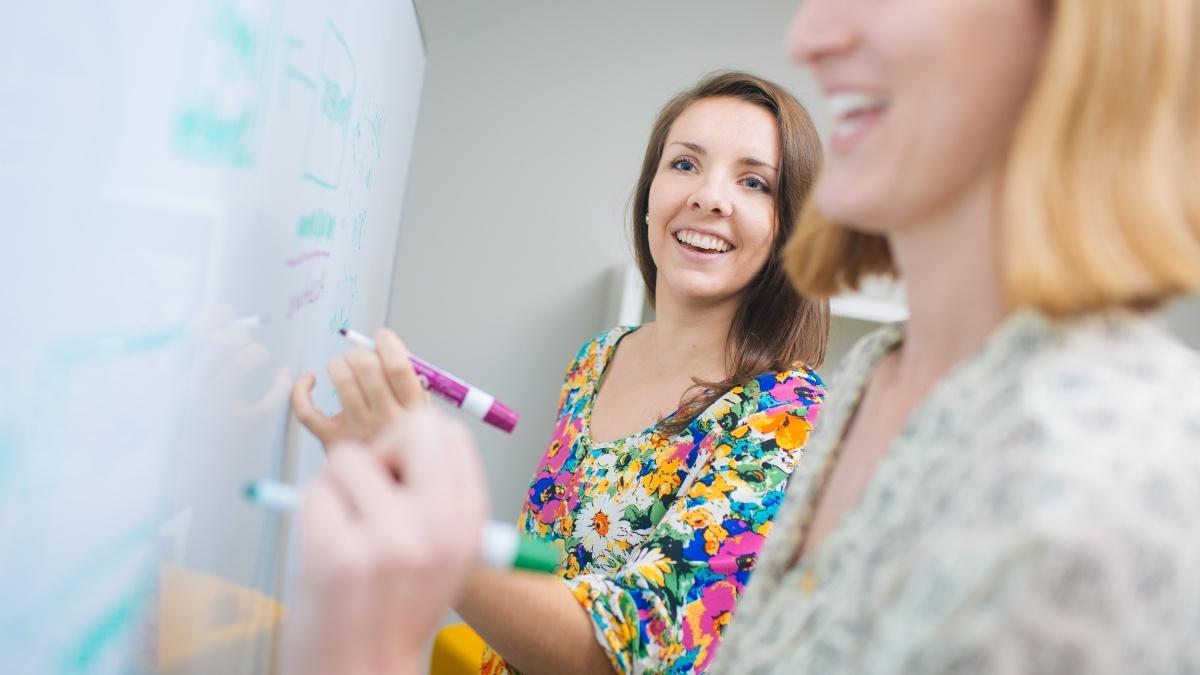 Trinity students writing on a white board. 