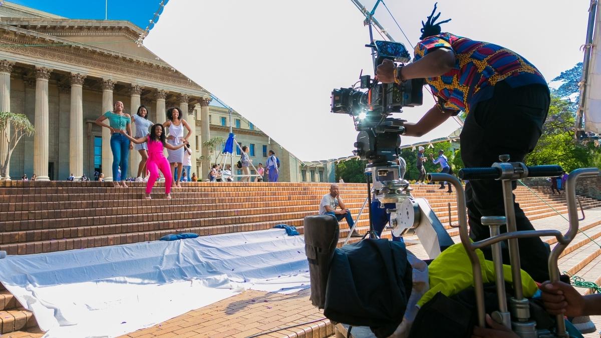 student in a director seat filming a group