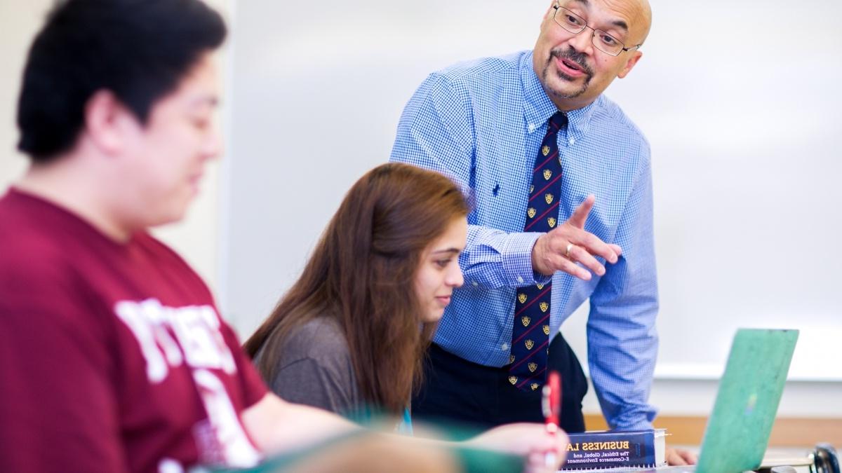 Professor working with two students on their laptops