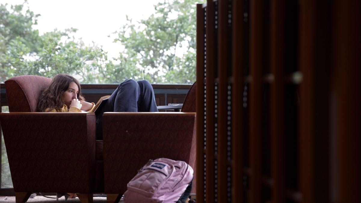 Student relaxes in a chair while reading a book